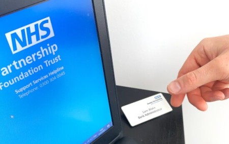 An NHS ID badge next to a computer monitor