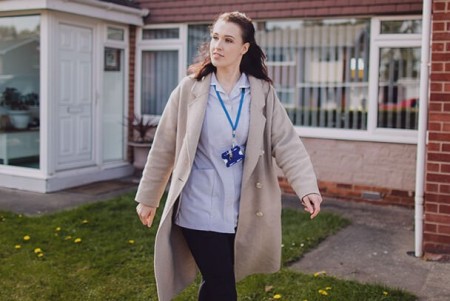 A health care support worker outside a house