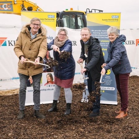 The team standing on the ground with spades in their hands breaking the ground in Bexhill for a new mental health hospital.