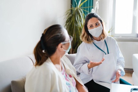 Two people wearing masks sat down and talking